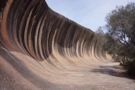 HD desktop wallpaper showcasing the unique rock formation known as Wave Rock near Perth, Australia, surrounded by natural hills and sparse vegetation.