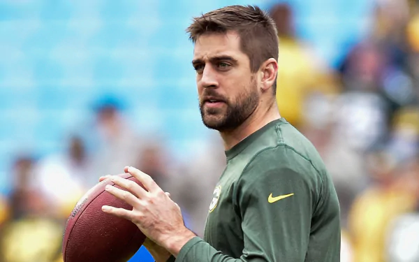 HD desktop wallpaper featuring an athlete holding a football, capturing the focused demeanor of Aaron Rodgers on the field.