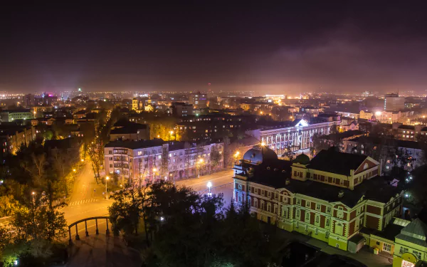 Panoramic night view of illuminated street and historic architecture in Irkutsk, Russia, captured in 4K Ultra HD with city lights glowing under a cloudy sky.