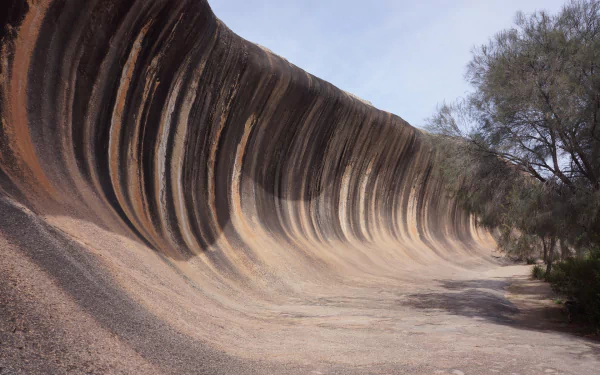 HD desktop wallpaper showcasing the unique rock formation known as Wave Rock near Perth, Australia, surrounded by natural hills and sparse vegetation.