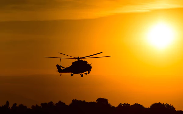 Silhouette of a Mil Mi-24 attack helicopter flying against a vivid orange sunset, captured in 4K Ultra HD as a military-themed desktop wallpaper.