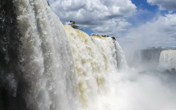Iguazu Falls cascading powerfully under a cloudy sky, captured in stunning 4K Ultra HD as a vibrant nature waterfall desktop wallpaper.