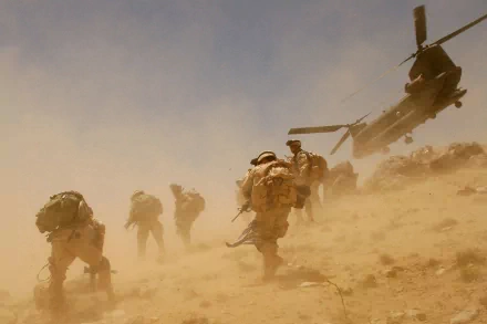 Soldiers advancing on dusty terrain with a Boeing CH-47 Chinook helicopter hovering nearby, captured in a high-definition military-themed desktop wallpaper.