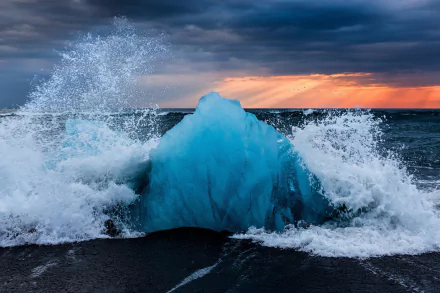 HD desktop wallpaper showing a frozen blue iceberg in the ocean with waves crashing under a dramatic winter sky on the horizon.