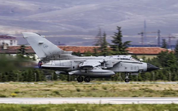 HD desktop wallpaper featuring a Panavia Tornado jet fighter warplane taxiing on a runway with a mountainous backdrop.
