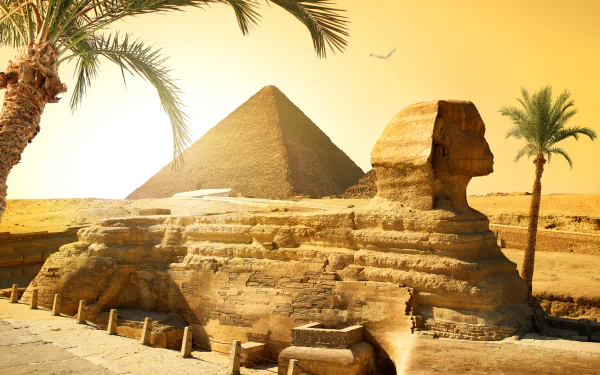 4K Ultra HD desktop wallpaper featuring the iconic Egyptian Sphinx with a pyramid in the background under a golden sky, framed by palm trees.