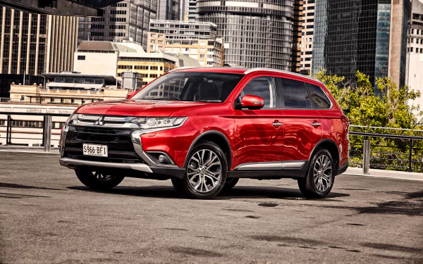A red Mitsubishi Outlander SUV parked in an urban setting, captured in 4K Ultra HD as a PC desktop wallpaper and background.
