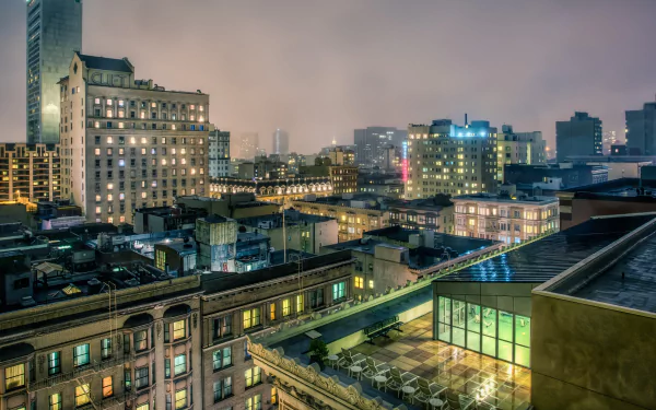 Night San Francisco cityscape from a rooftop, glowing buildings and streets rendered as a 2K Quad HD PC desktop wallpaper/background.