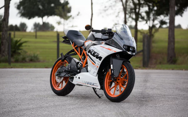 A sharp and striking KTM motorcycle is parked on a paved surface with lush green scenery in the background, captured in HD quality for a dynamic desktop wallpaper and background.