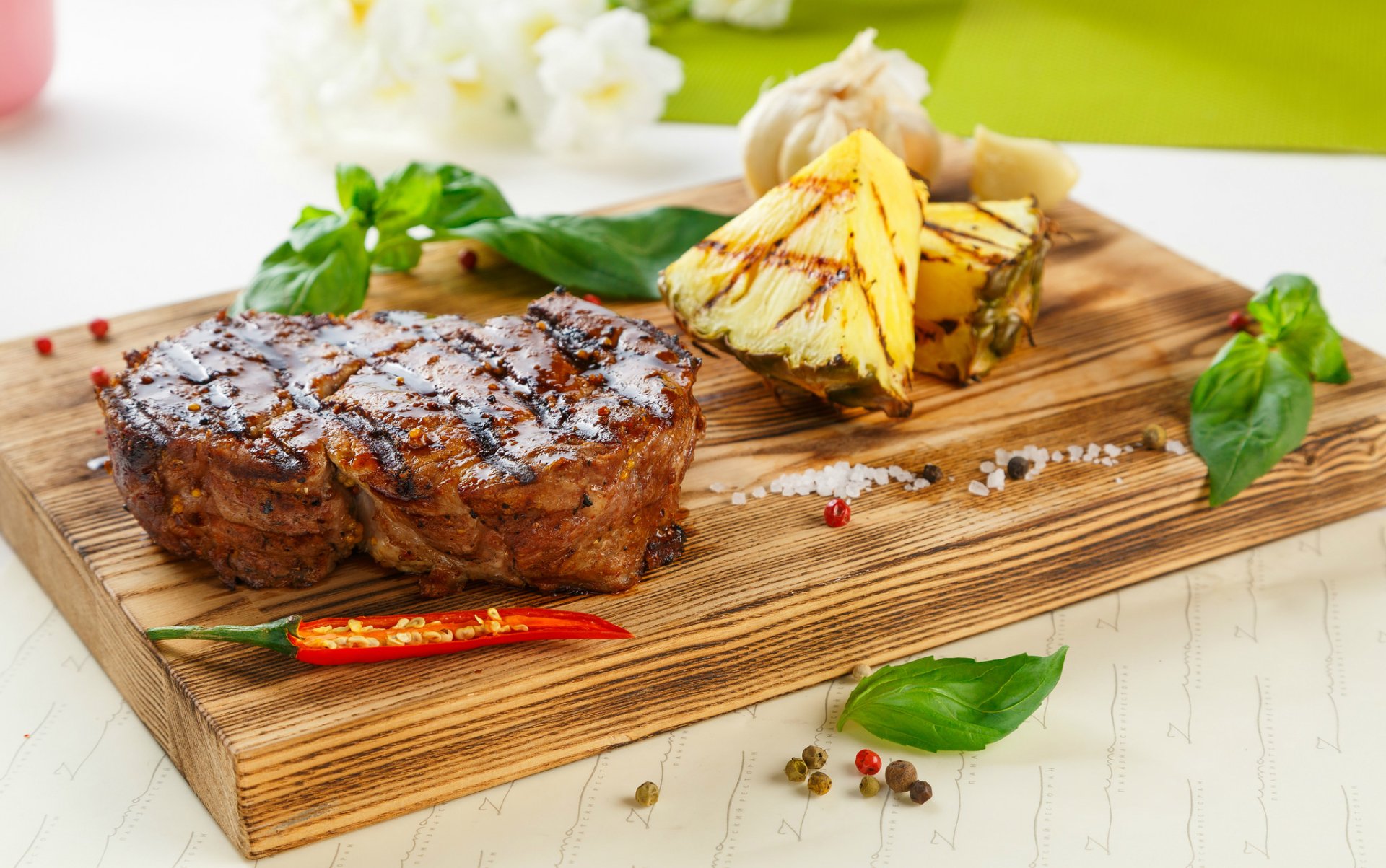Still life food meat — HD PC desktop wallpaper and background: grilled steak with char marks on a wooden board, pineapple wedges, chili, garlic and basil garnish.