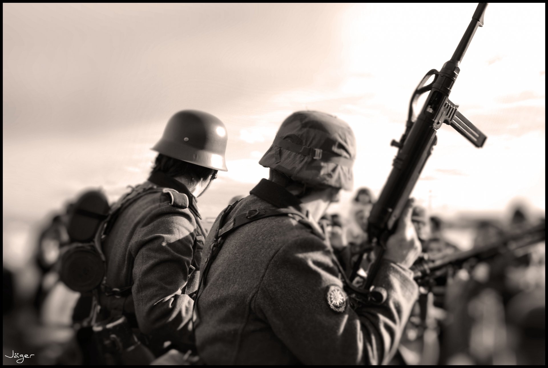 Sepia-toned artistic image of two military personnel in uniform, one holding a rifle, in focus against a blurred crowd background. This HD desktop wallpaper captures a historic wartime ambiance.