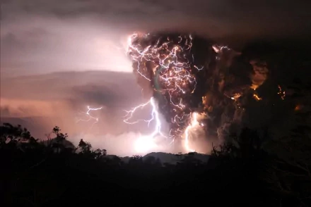 HD wallpaper of a volcanic eruption with dramatic lightning, capturing the power and intensity of nature. The dark sky and the lightning bolts amidst the ash clouds create a captivating scene.