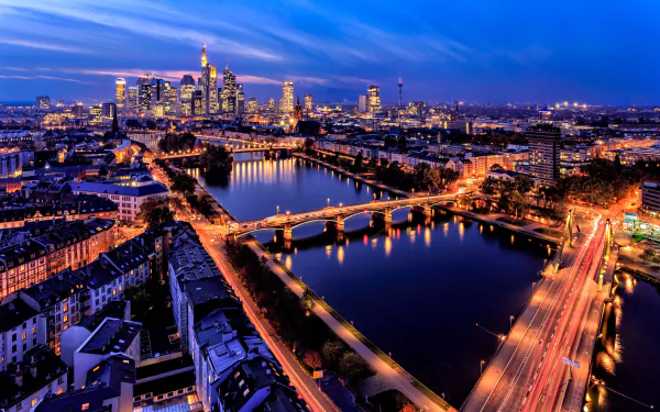 Nighttime cityscape of Frankfurt, Germany showcasing illuminated skyscrapers, buildings, and bridges over the river, captured as an HD PC desktop wallpaper background.