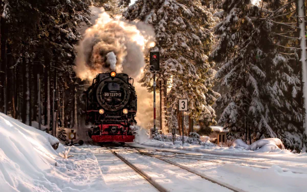 HD desktop wallpaper of a steam locomotive puffing smoke as it travels through a snowy winter landscape, surrounded by pine trees.