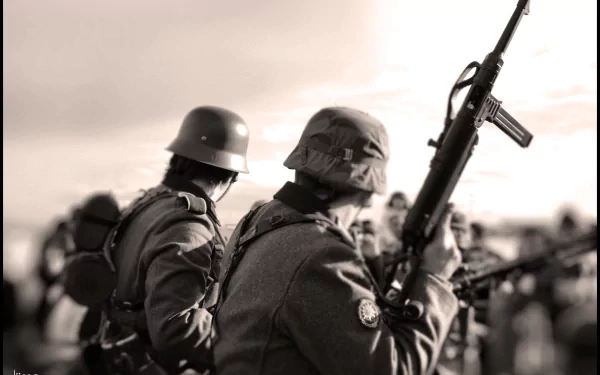 Sepia-toned artistic image of two military personnel in uniform, one holding a rifle, in focus against a blurred crowd background. This HD desktop wallpaper captures a historic wartime ambiance.