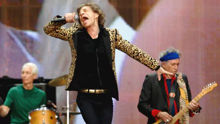 HD desktop wallpaper featuring The Rolling Stones performing live, highlighting Mick Jagger singing passionately with band members playing instruments in the background.