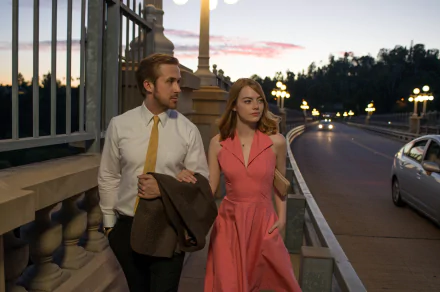 Emma Stone and Ryan Gosling walk together in a scene from the movie La La Land. The image, captured as a HD desktop wallpaper, depicts them on a bridge at dusk with streetlights glowing behind.