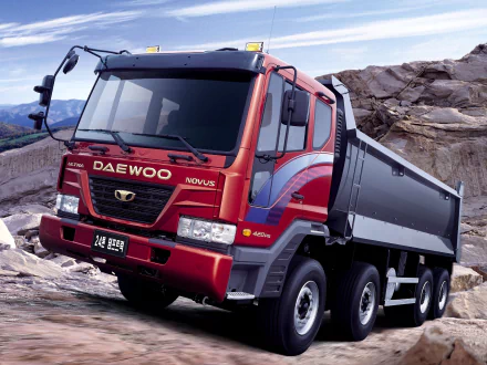 HD PC desktop wallpaper featuring a red Daewoo Novus heavy-duty dump truck parked on rocky terrain under a clear sky.