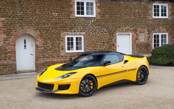 Yellow Lotus Evora supercar parked in front of a brick building, captured in 4K Ultra HD as a striking desktop wallpaper and background.