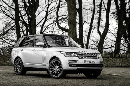 A sleek white Land Rover Range Rover SUV parked in a wooded area, showcasing its modern design and luxury features against a scenic backdrop.