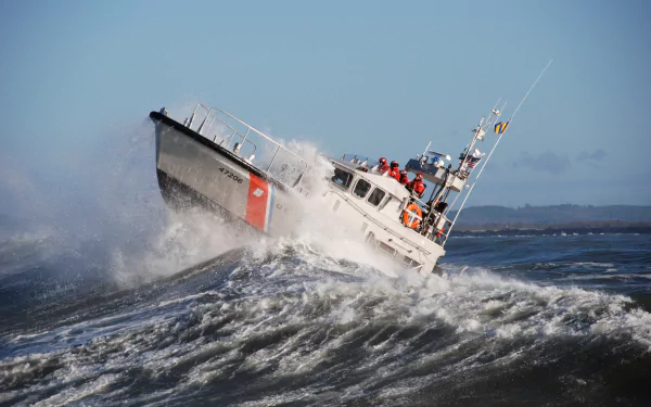 HD desktop wallpaper of a Coast Guard boat navigating a powerful ocean wave.