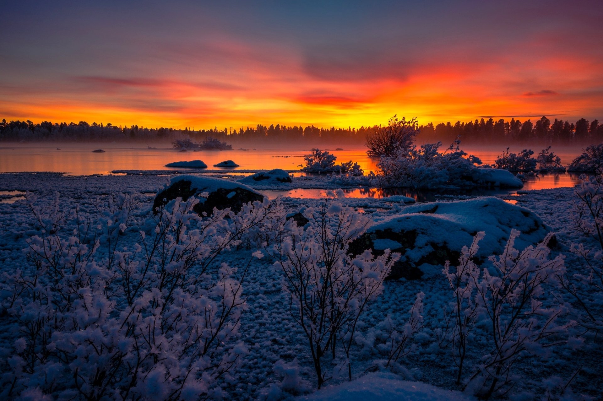 Winter sunset over a snowy lake with vibrant orange and purple skies, showcasing serene nature in this HD PC desktop wallpaper.