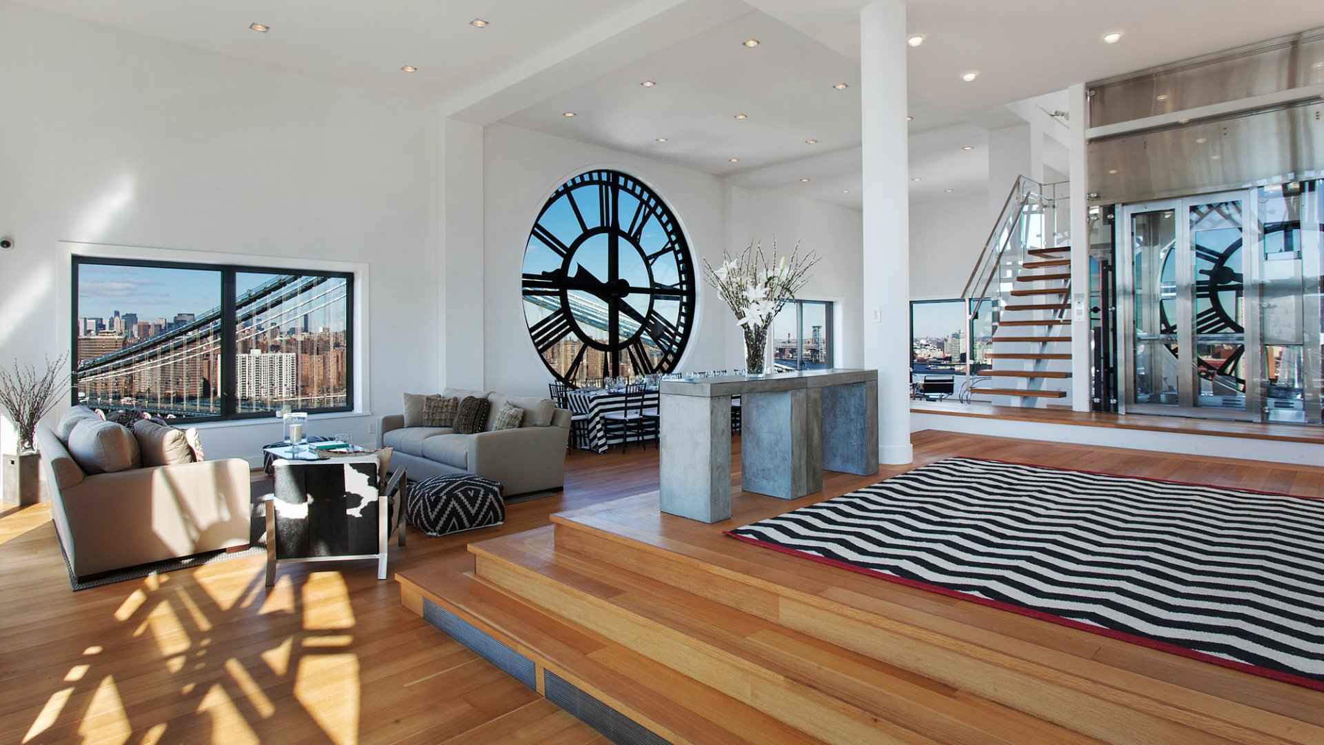 Spacious New York penthouse living room with a large man-made clock window, modern furnishings, and an open, sunlit layout.