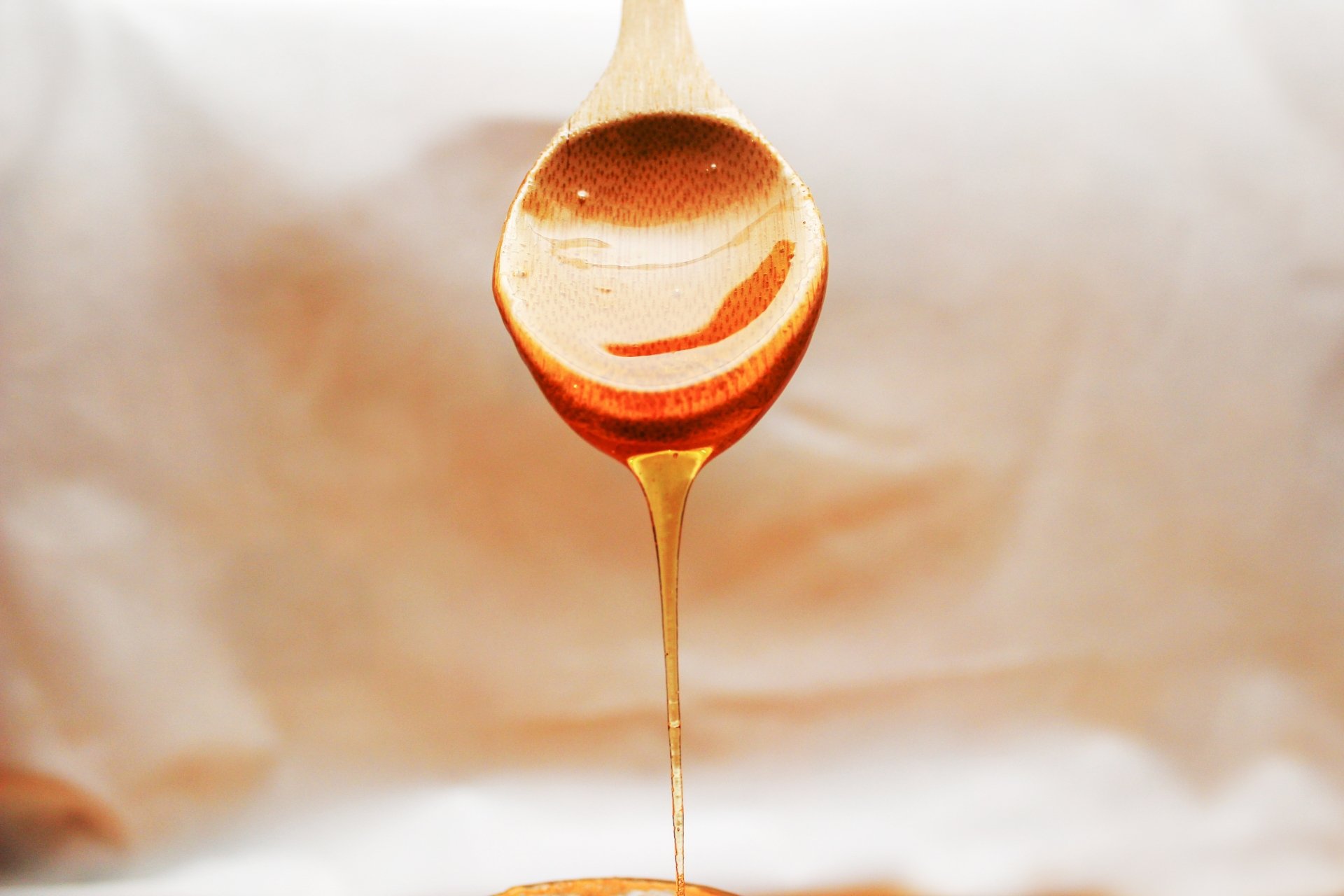 Close-up of golden honey dripping from a spoon, captured in stunning 4K Ultra HD as a rich food-themed PC desktop wallpaper.