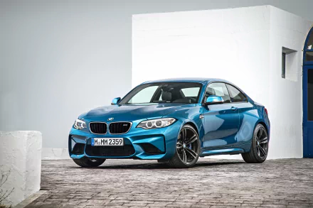 A blue BMW M2 sports car parked on a cobblestone driveway, showcased in a high-resolution 4K Ultra HD desktop wallpaper.