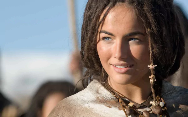 HD PC desktop wallpaper featuring a close-up of a smiling woman with dreadlocks from the movie 10,000 B.C., set against a soft blue sky background.