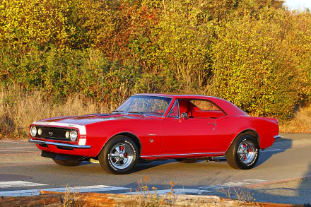 A vibrant red Chevrolet Camaro SS 350 muscle car and hot rod parked on a road with autumn foliage in the background, captured in an HD PC desktop wallpaper.