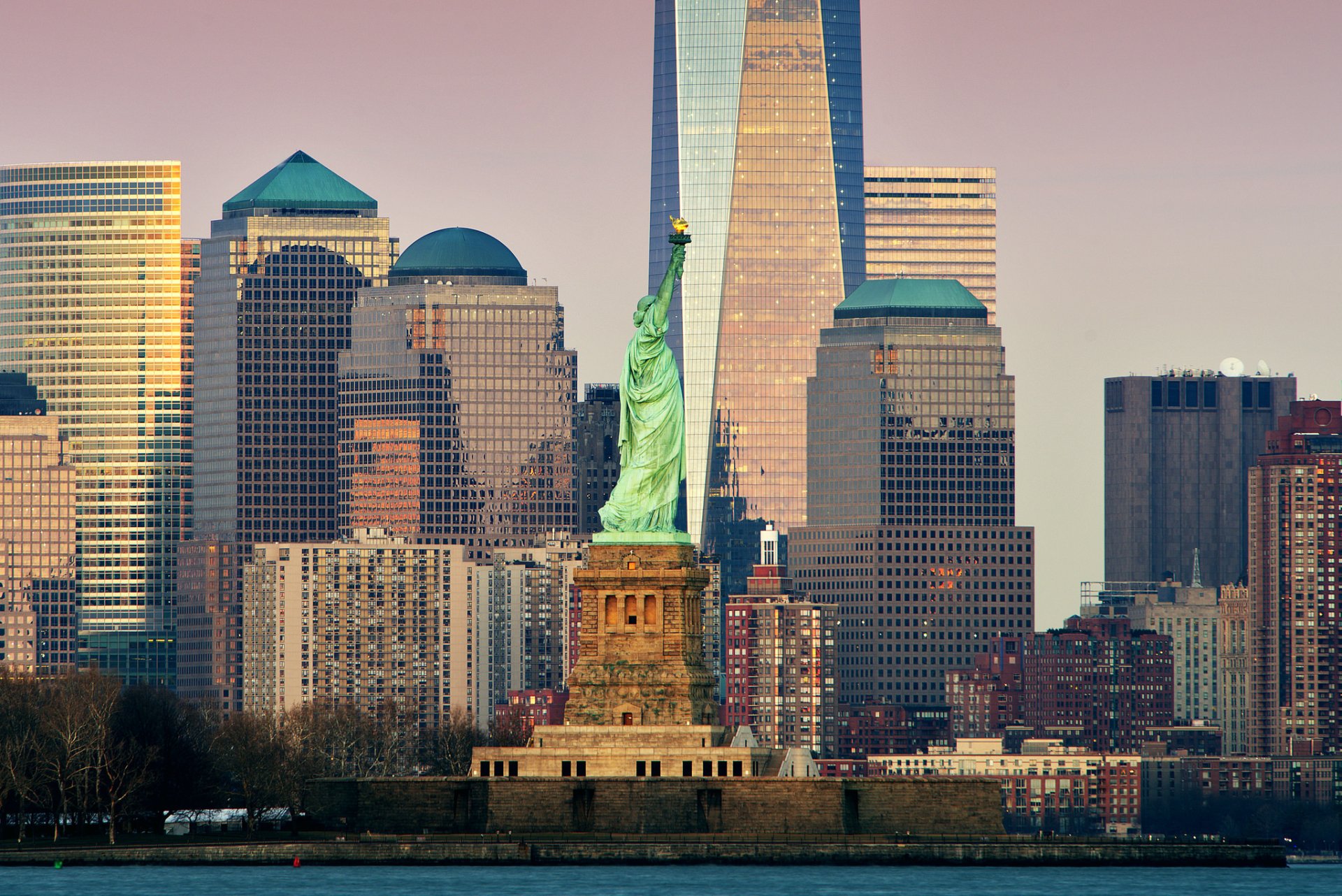 HD PC desktop wallpaper of the Statue of Liberty in New York, USA, standing before a man-made skyline of skyscrapers and buildings in Lower Manhattan.