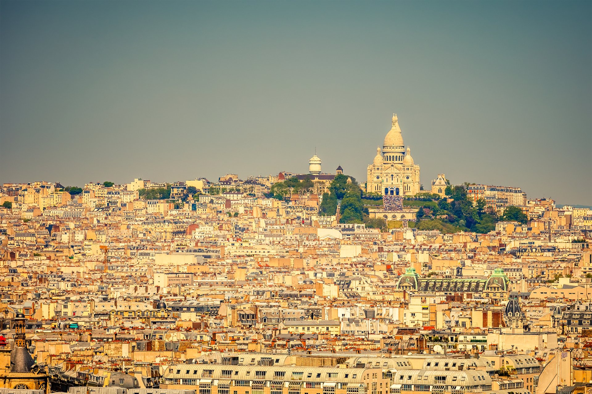 HD desktop wallpaper showing the Sacré-Cœur Basilica surrounded by city buildings in Paris, France, highlighting the iconic man-made architecture.