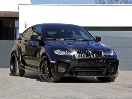 Black BMW X6 SUV parked in front of a modern garage, captured in high definition as a sleek car wallpaper and desktop background.