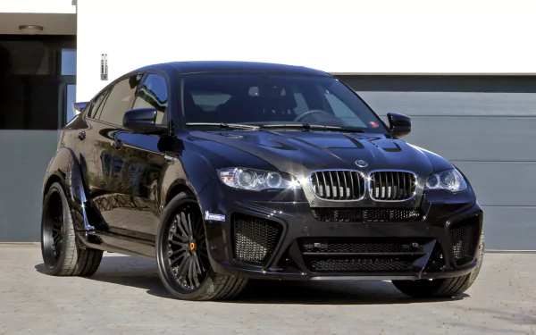 Black BMW X6 SUV parked in front of a modern garage, captured in high definition as a sleek car wallpaper and desktop background.