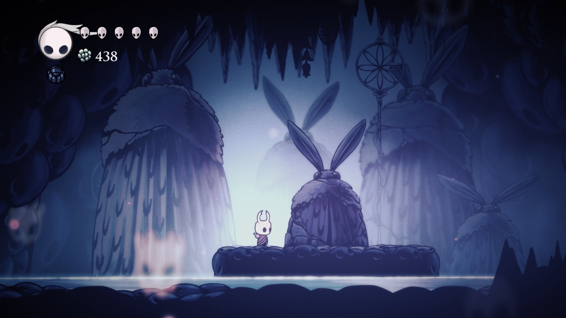 Hollow Knight video game 4K Ultra HD PC desktop wallpaper: the small white Knight stands on a dark ledge in a misty blue cavern with towering plant-like silhouettes.