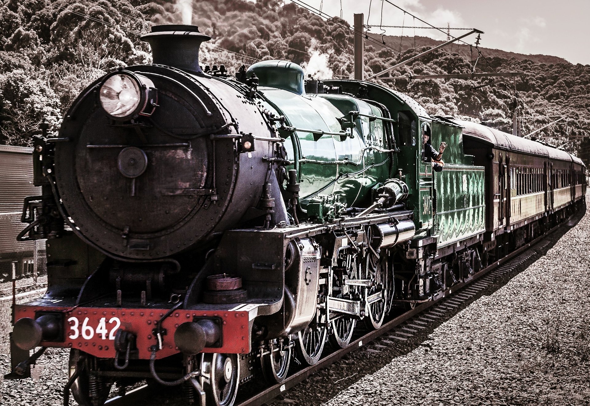 HD desktop wallpaper featuring a vintage locomotive train on a railway track, surrounded by natural scenery and hills in the background.