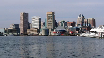 Baltimore skyline at the Inner Harbor: man-made waterfront with high-rise buildings and piers reflected on calm water — 2K Quad HD PC desktop wallpaper.