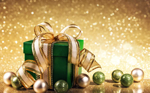 A 4K Ultra HD desktop wallpaper featuring a green gift box with a golden glittering ribbon, surrounded by gold and green baubles against a sparkling golden background.