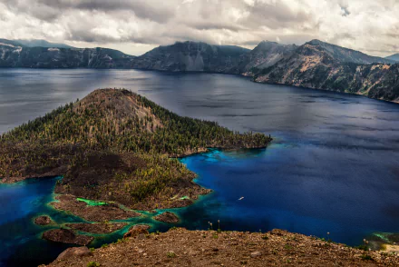 A stunning 4K Ultra HD view of Wizard Island in Crater Lake, Oregon, showcasing deep blue waters and surrounding forested mountains under a cloudy sky.