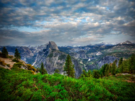 4K Ultra HD landscape of Yosemite National Park featuring dense forest, rugged mountains, and a dramatic cloudy sky, showcasing the park's natural beauty.