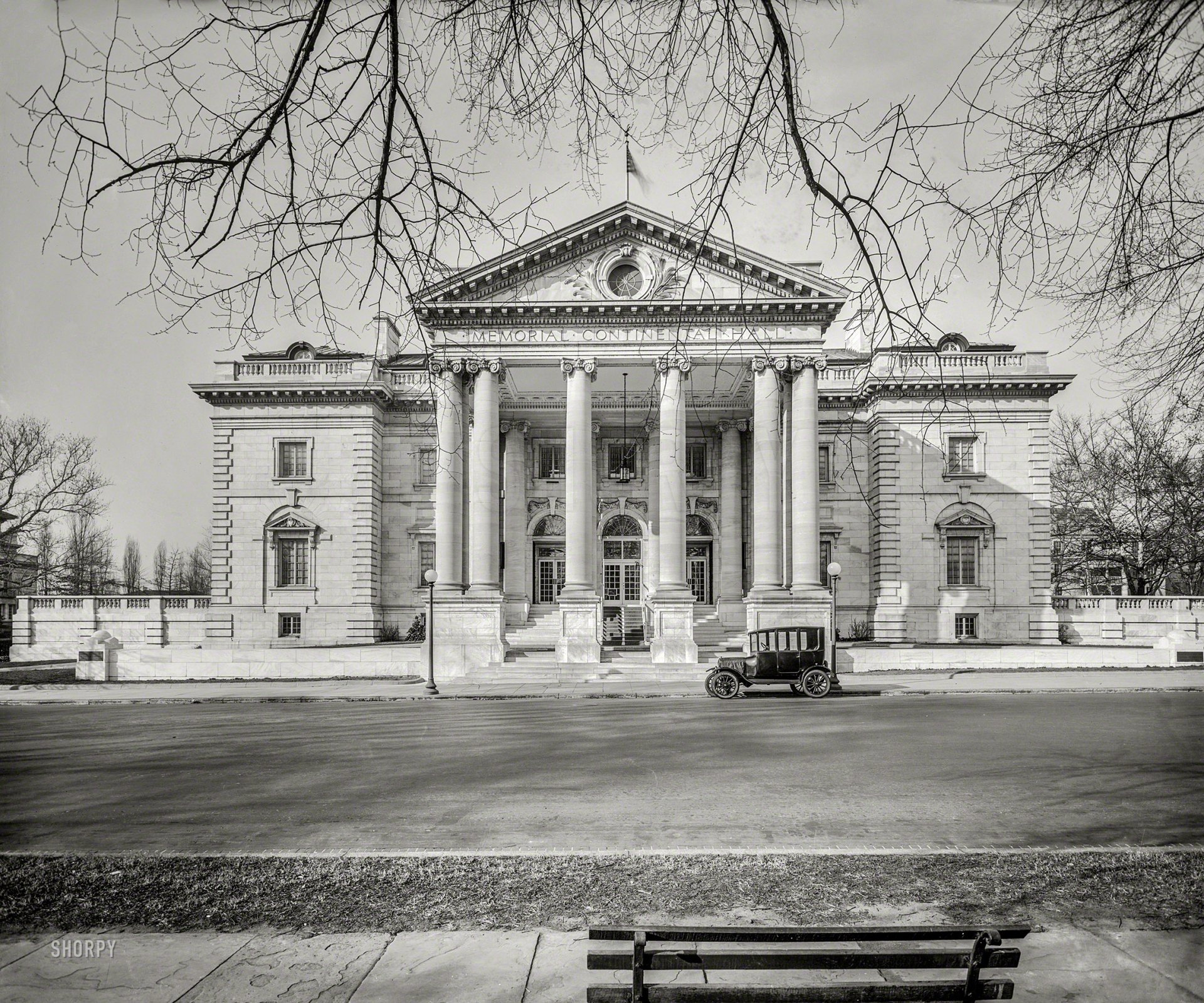 Black and white vintage photo of a classic car parked in front of the Memorial Continental Hall, showcasing historic architecture in Washington.