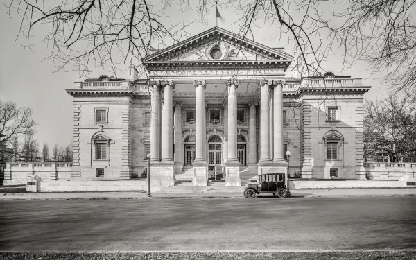 Black and white vintage photo of a classic car parked in front of the Memorial Continental Hall, showcasing historic architecture in Washington.