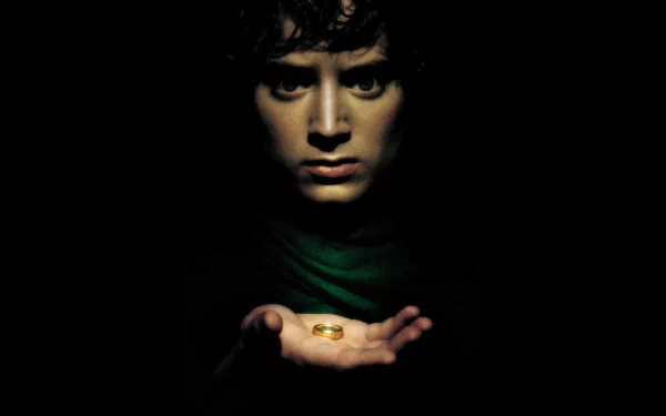 A dramatic HD desktop wallpaper from The Lord of the Rings: The Fellowship of the Ring, featuring a character holding a golden ring in a dimly lit setting.