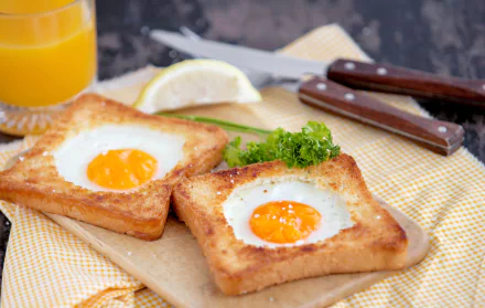 HD desktop wallpaper featuring a still life scene with toast and eggs, garnished with parsley, accompanied by a lemon wedge and orange juice in the background.