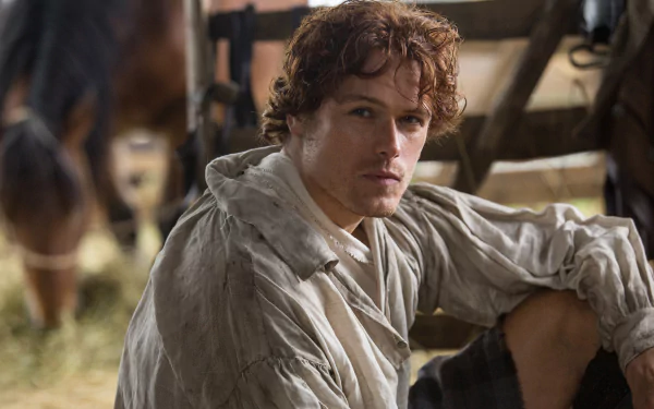 HD PC desktop wallpaper featuring Sam Heughan as Jamie Fraser from the TV show Outlander, capturing a rustic, historical setting.