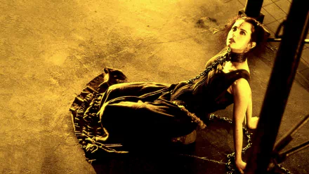 HD PC desktop wallpaper of a gothic woman in a dark dress chained to a post under dramatic yellow lighting, evocative of the film The Crow: City of Angels.