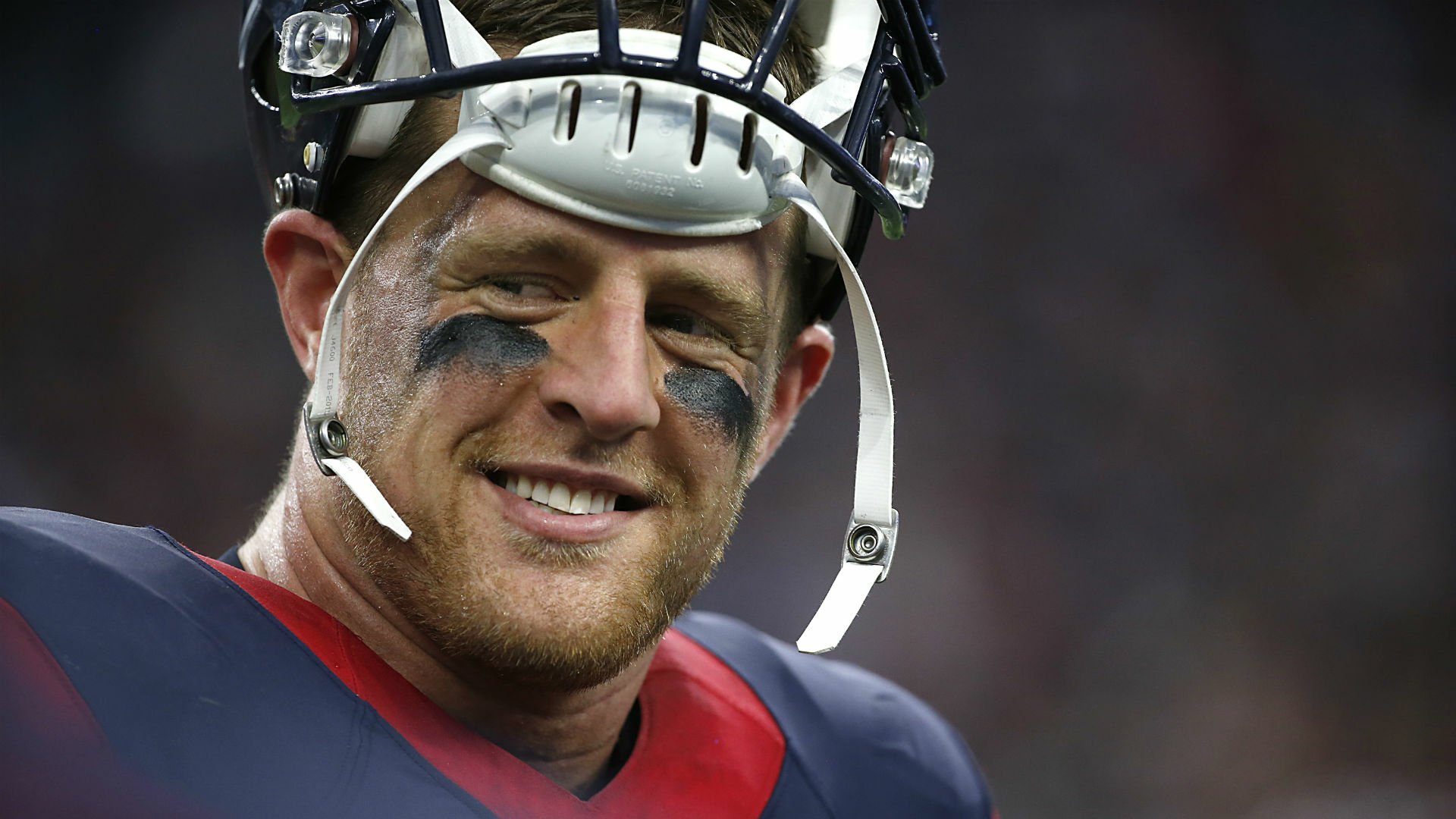 HD PC desktop wallpaper featuring J.J. Watt in sports gear, smiling with a football helmet and eye black during a game.