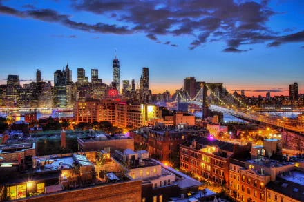 HD desktop wallpaper capturing New York City's illuminated skyscrapers and Brooklyn Bridge at night, showcasing vibrant city lights and the urban skyline.