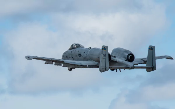 A Fairchild Republic A-10 Thunderbolt II jet fighter soars through a cloudy sky, showcasing its military prowess in this stunning 4K Ultra HD wallpaper.